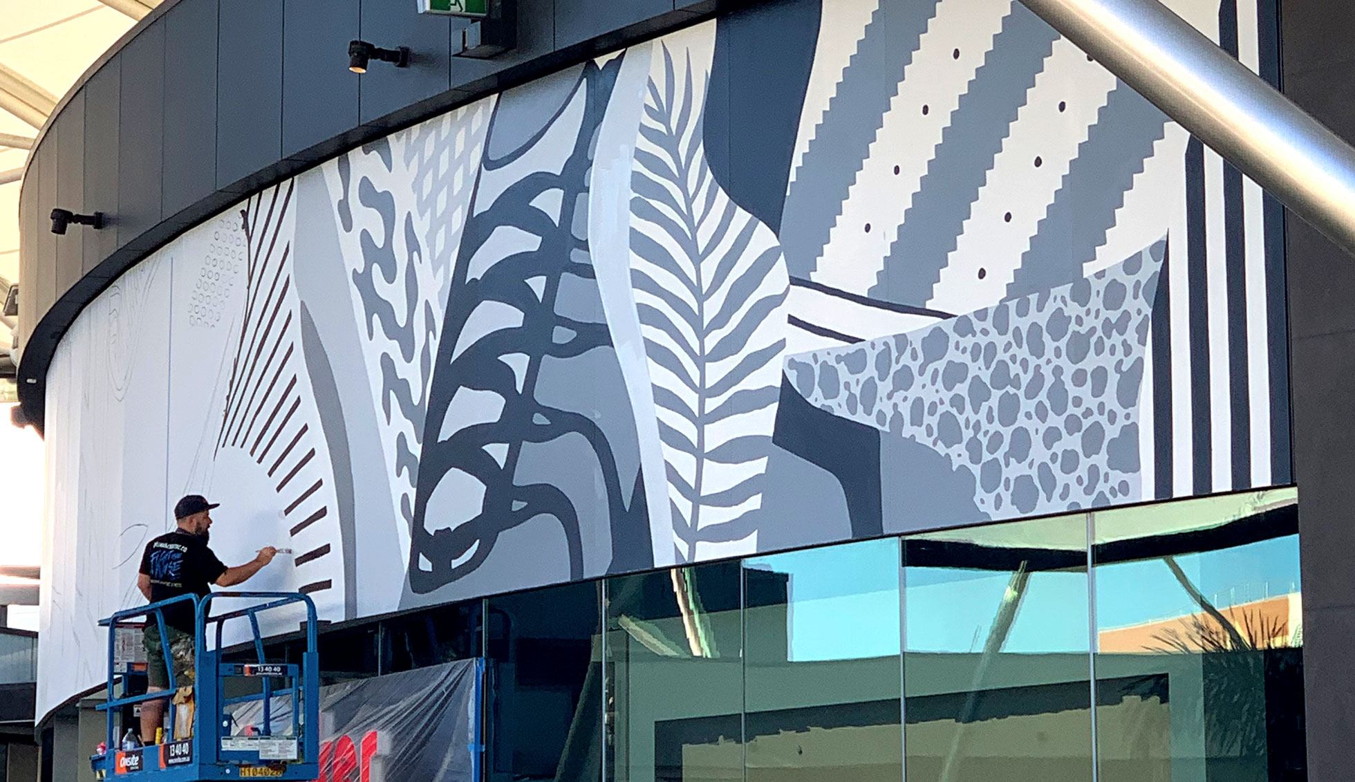 Mural artist Kiel Tillman working on a large-scale mural at Pacific Fair Shopping Centre, Gold Coast