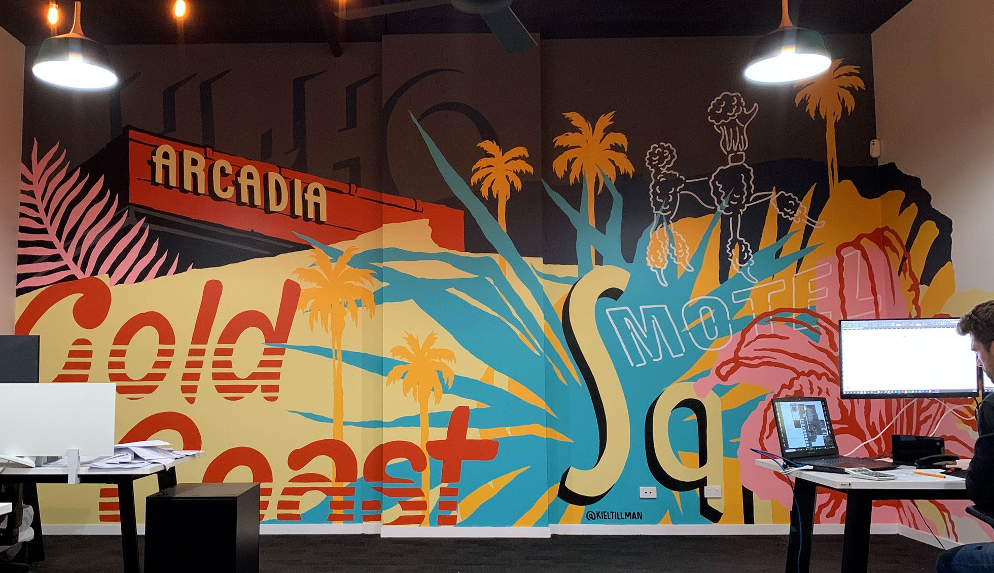 A finished mural piece on an office wall featuring typography and tropical imagery