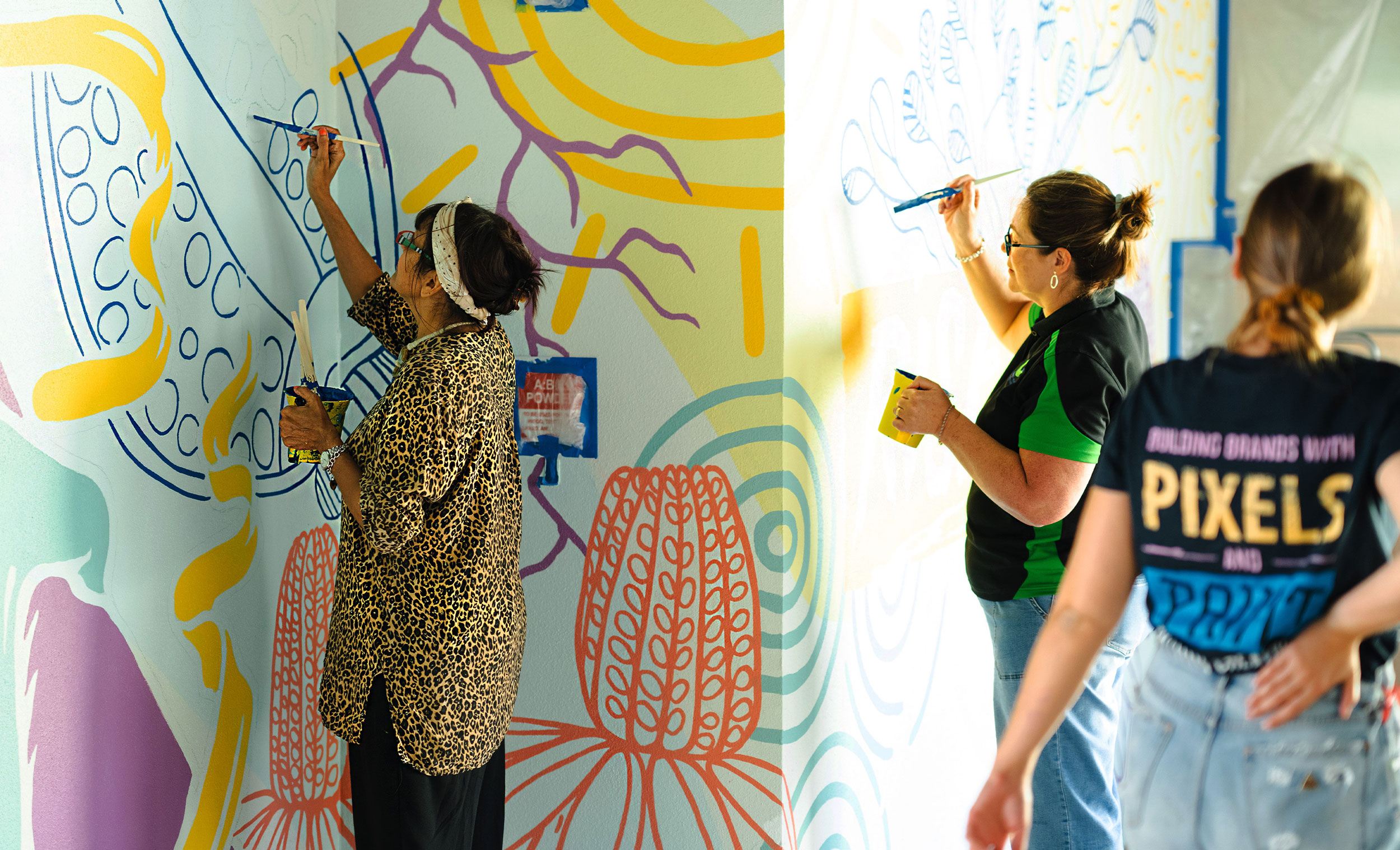 Artist Lisa Sorbie paints the mural alongside youth worker Connie